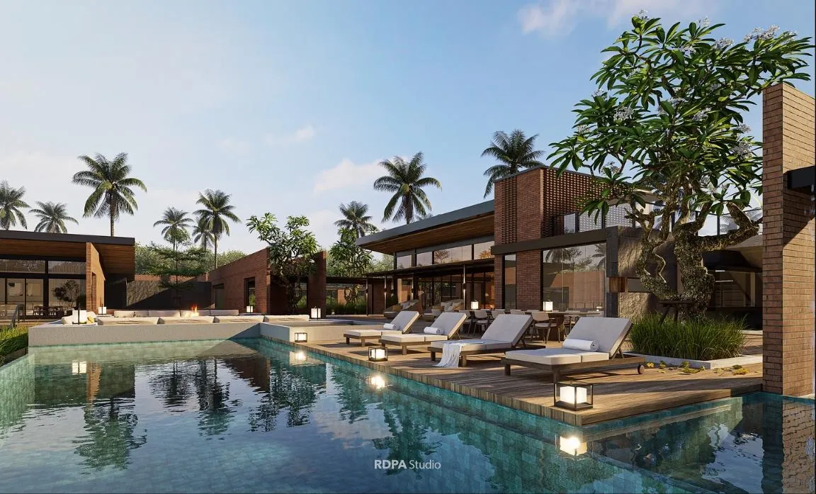 Pool at dusk with loungers on timber decking and palms behind the brick wall
