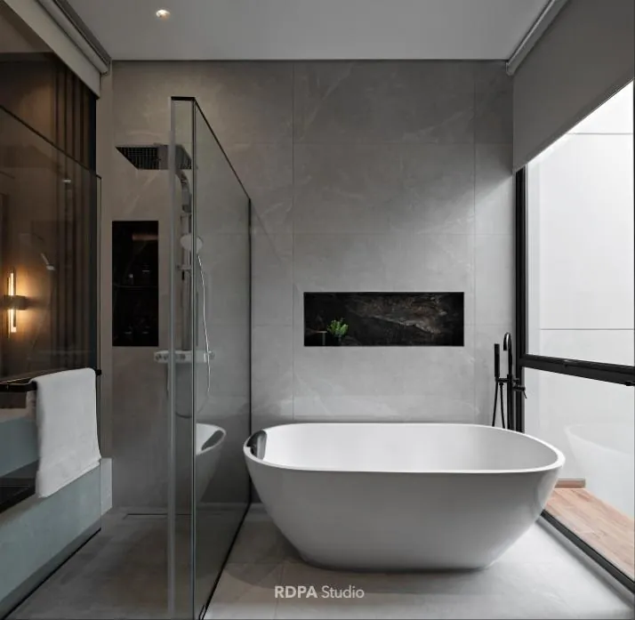 Bathroom in grey stone with a freestanding tub beside a full height window